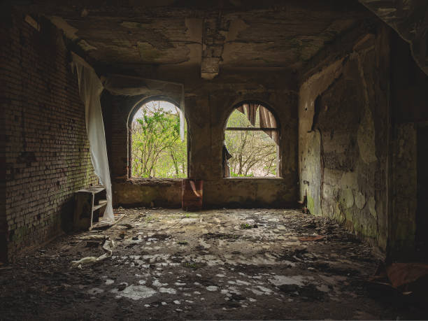 istock Arched windows in a dark decaying abandoned old room. Crumbling wall inside a dark abandoned room. Walk through the old ruins. Ghost town. War torn place 1425212655