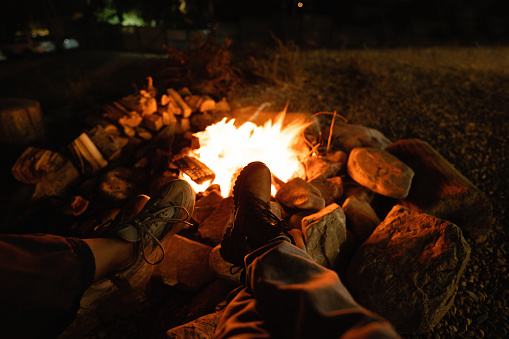 Close-up of women's legs in boots against the background of a fire. Night photography.