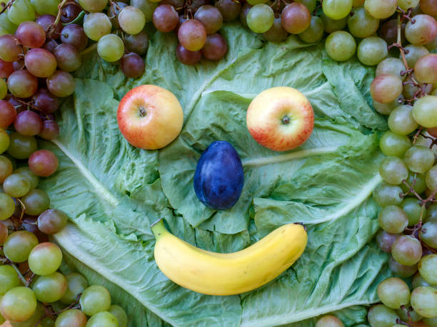 Funny face made of fresh fruits - grapes, apples, plum and banana