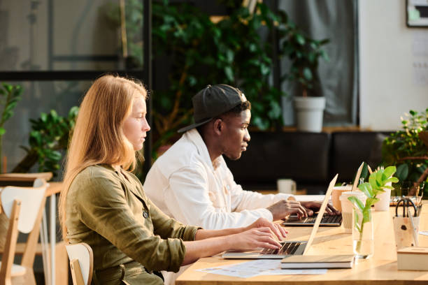 istock Side view of two young intercultural designers or analysts networking by desk 1425222217