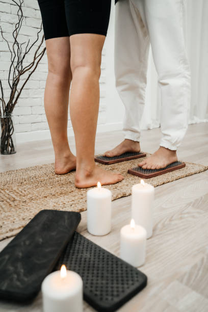 A girl helps a man to stand on nails. Sadhu board. Pleasant atmosphere white candles relaxation. Concept on healthy lifestyle. stock photo