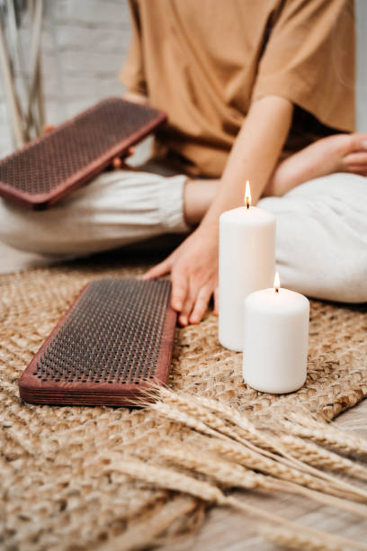 The girl is holding a Sadhu Board in her hands. Close-up. White candles. Concept on healthy lifestyle. stock photo