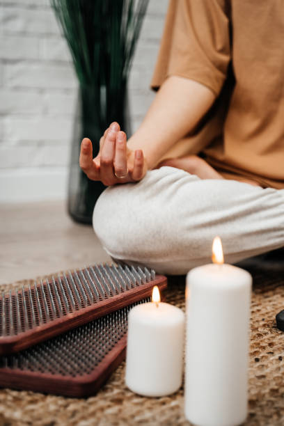 The girl meditates with lit white candles. Sadhu board. Concept on healthy lifestyle. stock photo