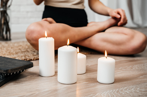 The girl meditates with lit white candles. Sadhu board. Concept on healthy lifestyle.