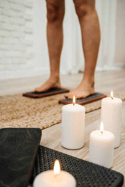 The legs of a girl standing on nails with lit white candles. Sadhu Board. Concept on healthy lifestyle. stock photo