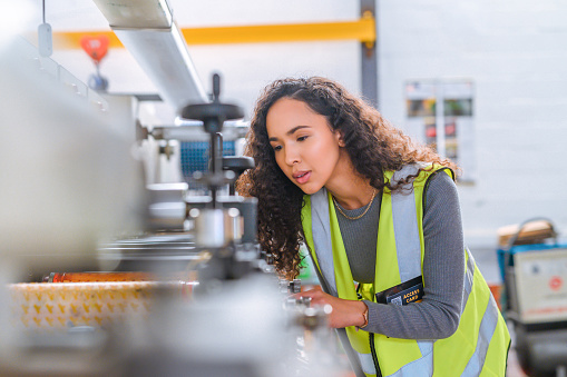 Mechanic engineer working on maintenance and upgrade on hardware in a production factory. Woman machine expert or professional working on a engineering production line in a warehouse or workshop