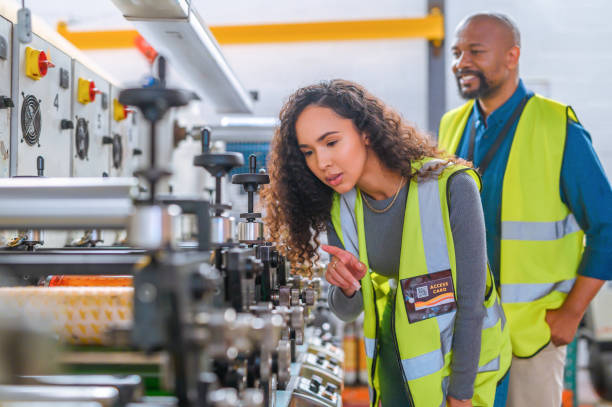 istock Team, industrial and engineering with machine for electrical technology at factory warehouse. Technician employee workers of a man and woman checking mechanical machinery for industry work inspection 1425227238