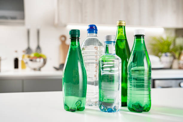 Collection of various plastic water bottles on kitchen counter Close up view of various plastic water bottles shot on kitchen counter. Selective focus on bottles. Copy space. High resolution 42Mp indoors digital capture taken with Sony A7rII and Sony FE 90mm f2.8 macro G OSS lens bottled water on table stock pictures, royalty-free photos & images