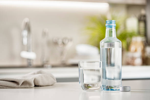 Close up view of a plastic water bottle and drinking glass shot on kitchen counter. Selective focus on foreground. High resolution 42Mp indoors digital capture taken with Sony A7rII and Sony FE 90mm f2.8 macro G OSS lens