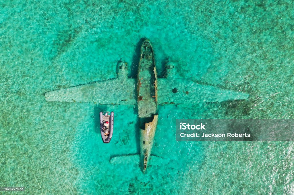 Plane crash with small boat over top Aerial view of a plane crash with a boat on top Bahamas Stock Photo