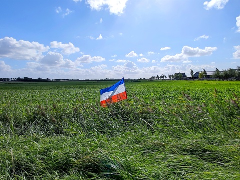 Inverted dutch flag placed in a farmers meadow by protesting farmers that are protesting against the nitrogen policy. There are no people or trademarks in the shot.