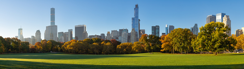 New York City view of Central Park Sheep Meadow in Fall. Panoramic morning view of the Midtown Manhattan Billionaires' Row skyscrapers