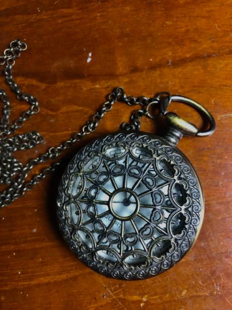 istock Black hollow spider web quartz pocket watch on the wooden table 1425233510