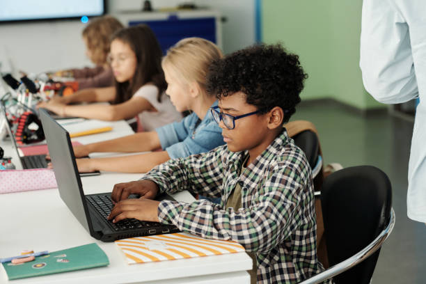 seitenansicht eines jugendlichen afroamerikanischen schülers, der vor dem laptop arbeitet - klassenzimmer stock-fotos und bilder