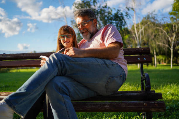 istock Senior man reading book with grand daughter. 1425237326