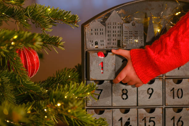 advent calendar.a child hand in a red sweater opens the advent calendar near christmas tree . christmas traditions and symbols. gifts and surprises for christmas and new year. - julkalender bildbanksfoton och bilder