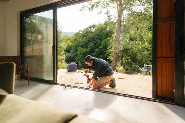 istock Man working on wooden decking in front of a cabin house 1425247802