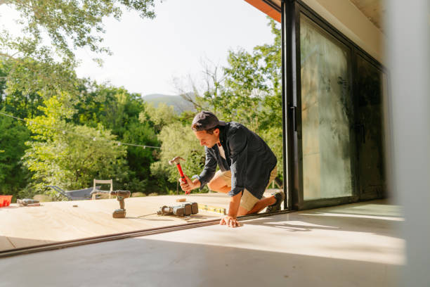 istock Man working on wooden decking in front of a cabin house 1425247941