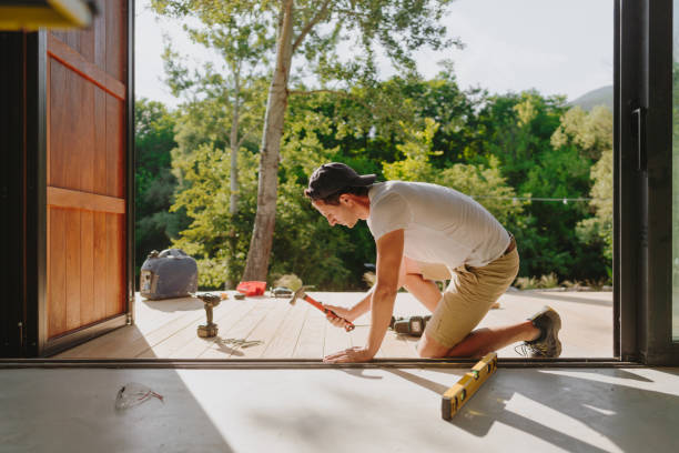 Man working on wooden decking in front of a cabin house stock photo