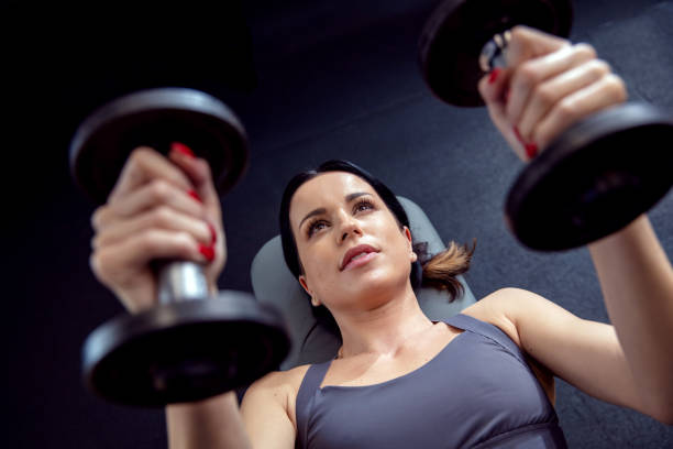istock Fit and attractive brunette workouts with dumbbells in her hands 1425248256