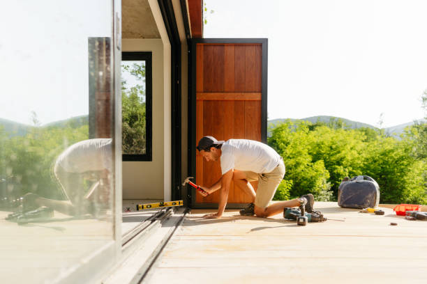 istock Man working on wooden decking in front of a cabin house 1425248355