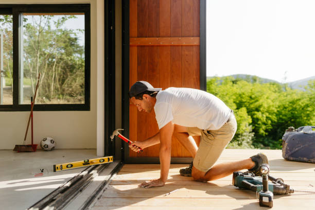 istock Man working on wooden decking in front of a cabin house 1425248357