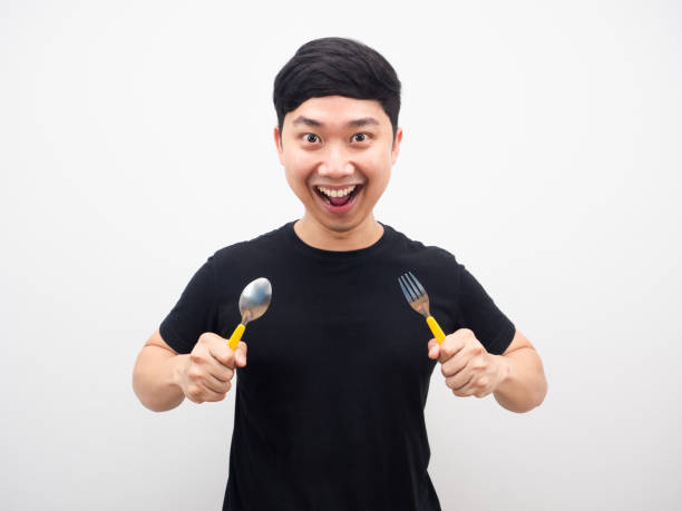 istock Man holding spoon cheerful and feeling hungry white background 1425248571