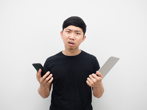 Asian man holding tablet and mobile phone serious and strain emotion