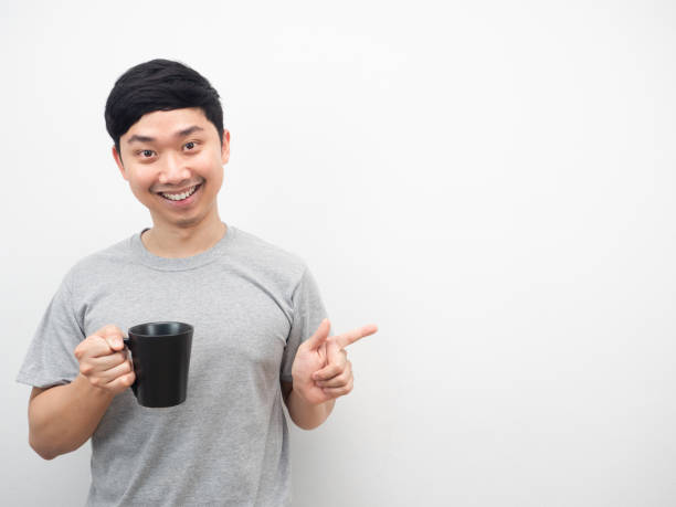 istock Man holding coffee cup with smiling and point finger at copy space 1425248880