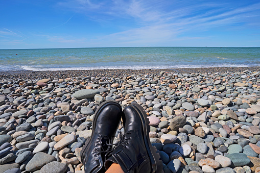 Women Boots shoes and Black sea Batumi Adjara Georgia Country for Concept Idea Relax on th epebbles Beach