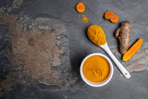 istock turmeric powder in spoon with turmeric root. curcuma or curcumin on concrete background. Spice, natural coloring, alternative medicine. Long banner format. top view 1425250669