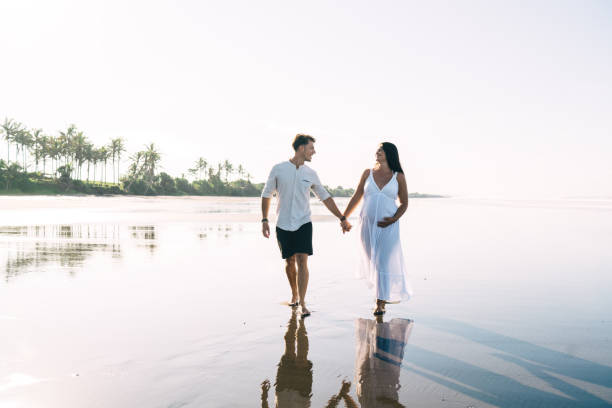 istock Loving pregnant couple strolling on wet sand 1425250761