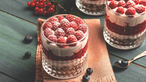 istock Healthy raspberry fruit dessert with skyr yogurt, granola layered in jar surrounded by ingredients, Vegetarian breakfast, fresh raspberries and blueberries yoghurt 1425255011