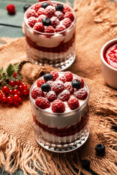 istock Healthy raspberry fruit dessert with skyr yogurt, granola layered in jar surrounded by ingredients, Vegetarian breakfast, fresh raspberries and blueberries yoghurt 1425255047