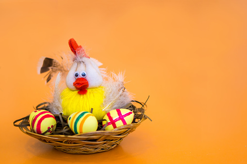 Chicken sitting in a basket with painted eggs. Easter souvenir.