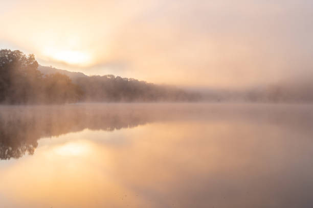 istock Sun rising behind hillside with a fog-covered lake. 1425255898