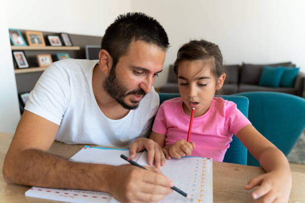 istock Father and daughter sitting at the table indoors, doing homework. 1425256023