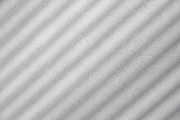 istock Diagonal blinds shadow on a white plastered wall, black and white style backdrop 1425256164