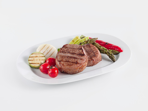 Grilled steaks with grilled vegetables on a white background