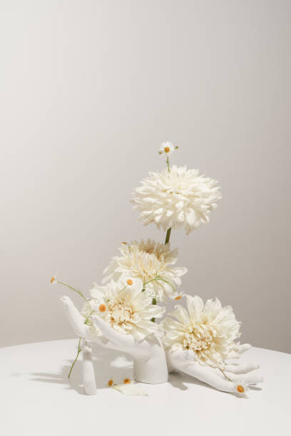 istock Two white artificial hands on a white table hold a flower arrangement. Modern floristry 1425264669