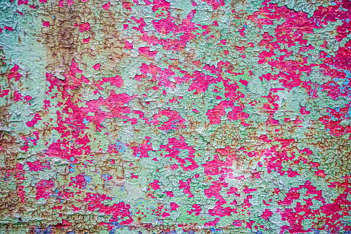 Rusty background. A rusty old metal plate with cracked green and pink gloss paint