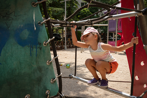 Little girl playing on playground, hanging walk along monkey bars