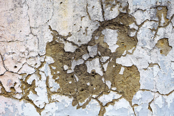 istock Cracked and distressed painted surface on the side of a building or wall. Concrete or cement texture with aged paint peeling off. 1425268073