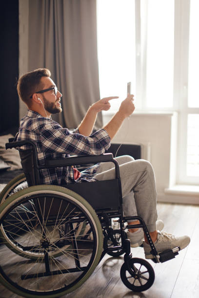 istock Man in wheelchair pointing finger while chatting on tablet 1425273065