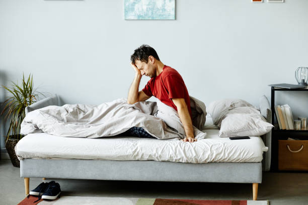 Exhausted man waking up in the morning Exhausted mature man waking up in the morning, he sitting on bed and rubbing his eyes hangover stock pictures, royalty-free photos & images