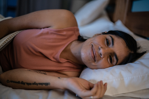Portrait of mid adult woman waking up in bedroom at home