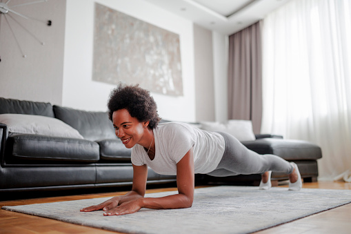 Healthy woman holding plank position at home