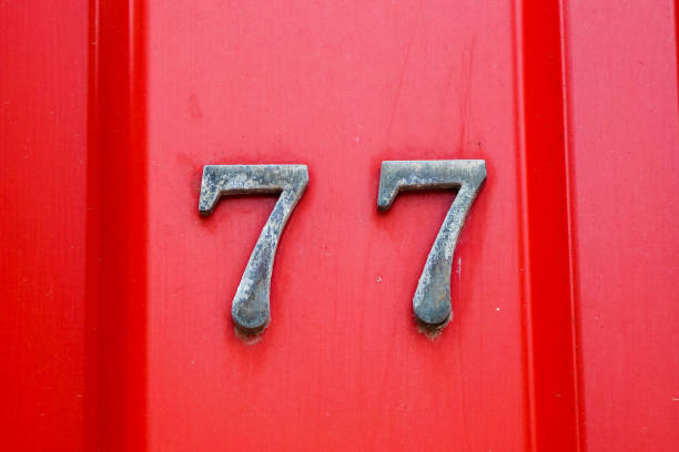 house number 77 on iron red background, seventy-seven