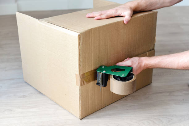istock man using a tool to seal a cardboard box with brown duct tape 1425283382