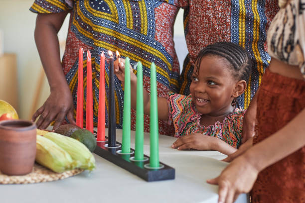 petit enfant brûlant des bougies pour les vacances - kwanzaa photos et images de collection